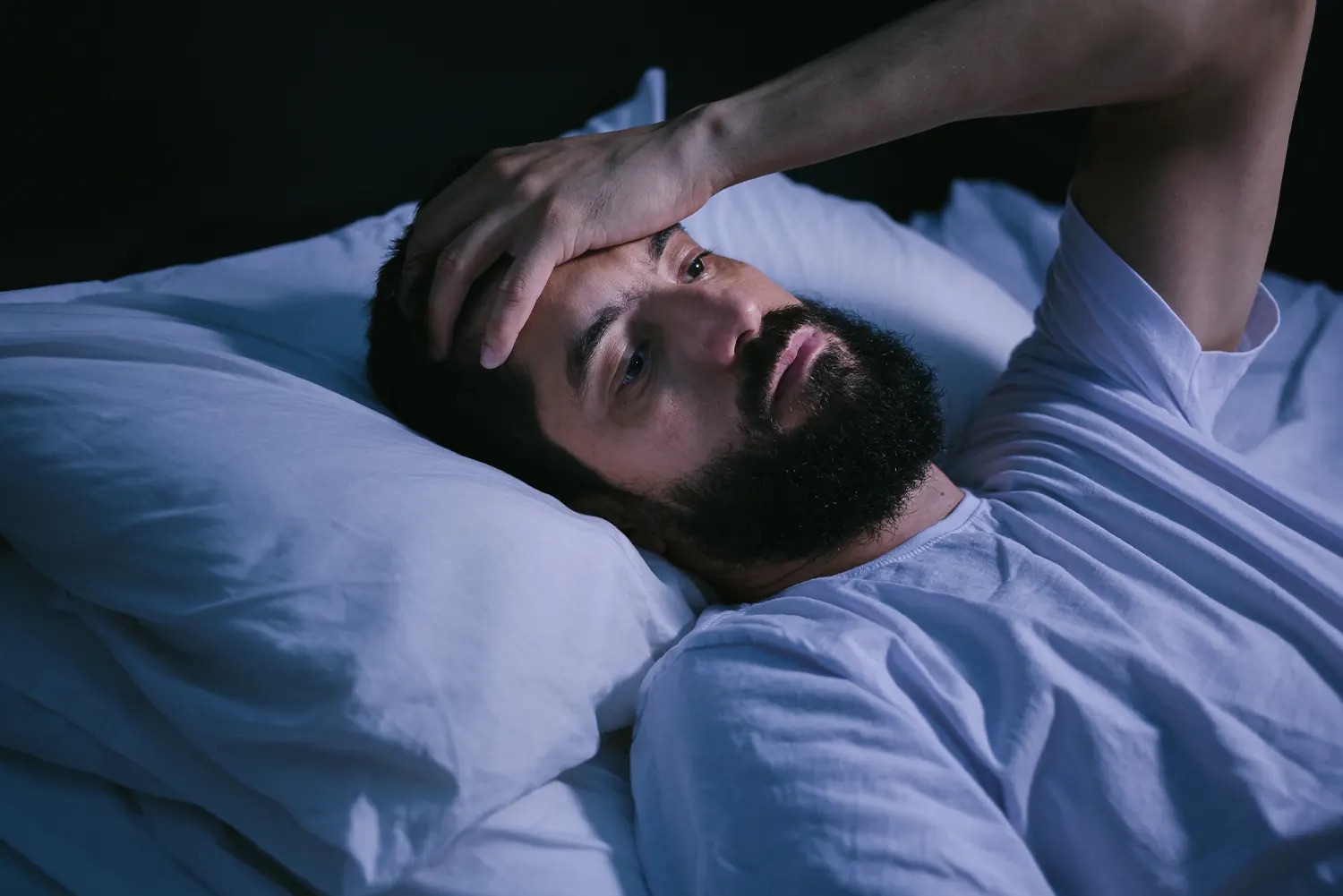 man in bed with hand on his head