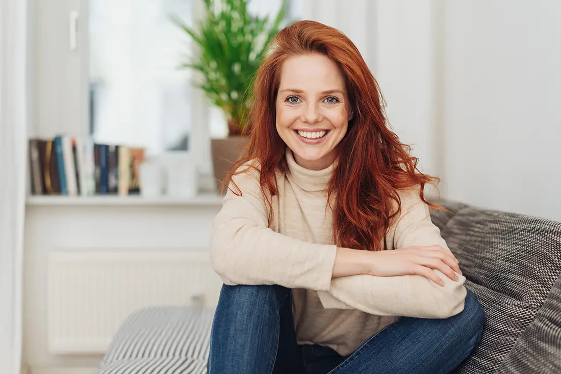 red-haired woman on couch smiling