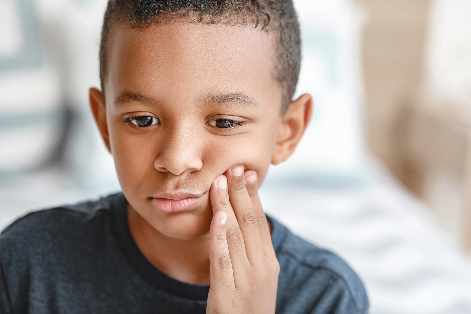 Child holding jaw in discomfort