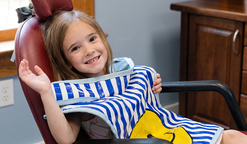 Smiling girl waving from the dental chair