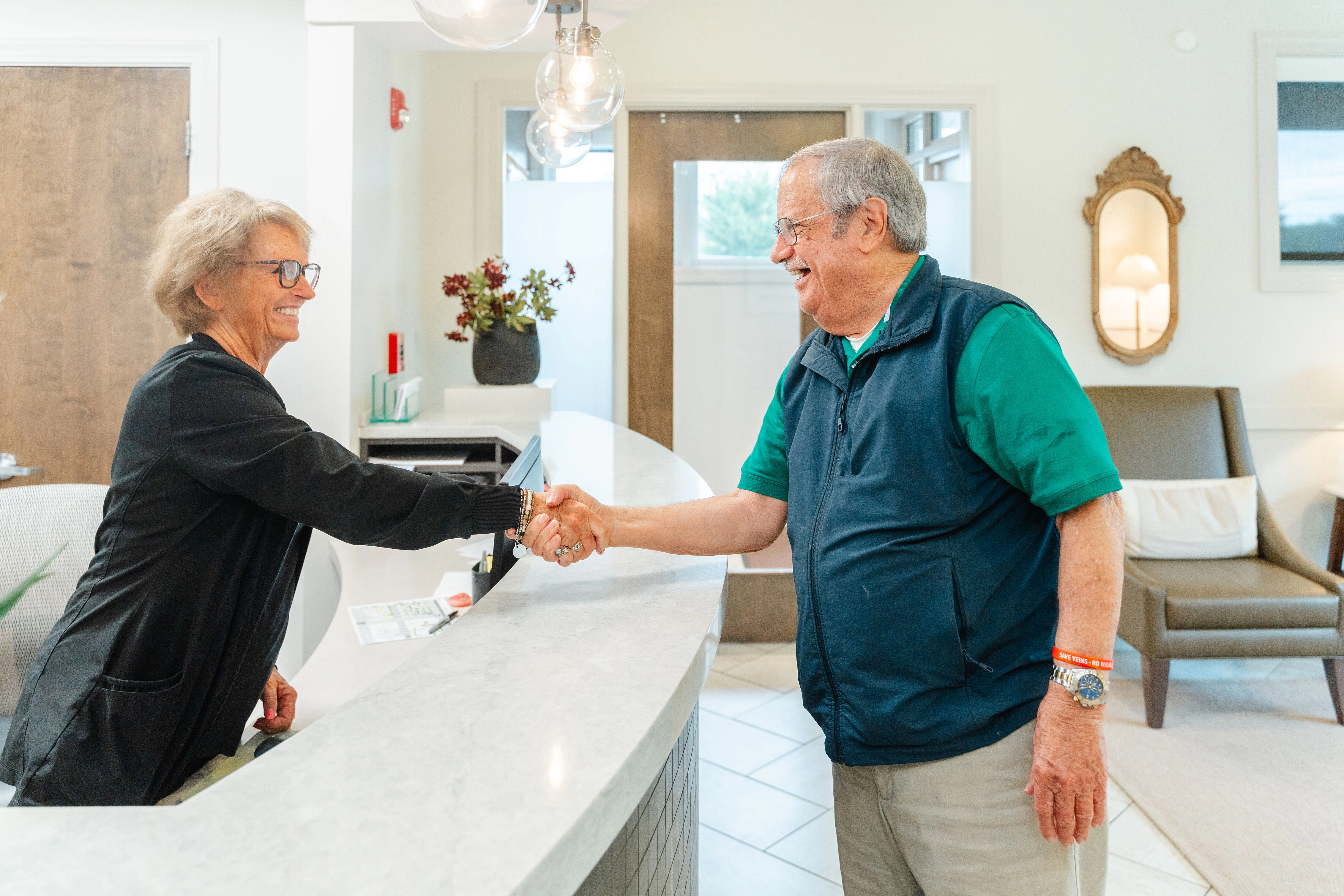 Receptionist and older man shaking hands